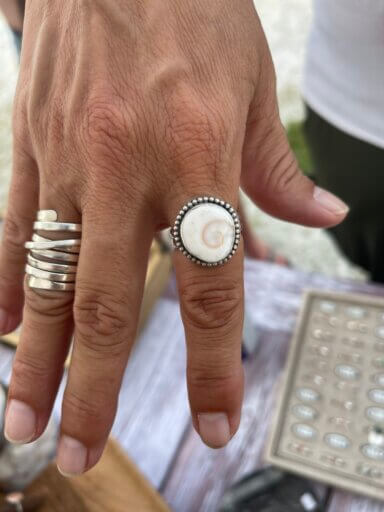 Changing Tides Jewelry showing off a ring that has a subtle nautilus spiral in it, as example of their work for Gallery Night.