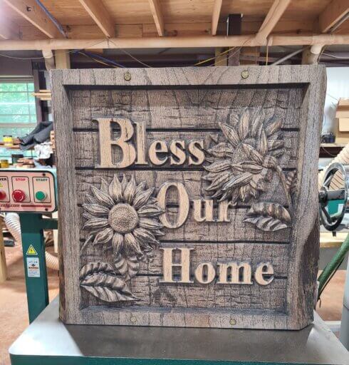 Gallery Night artist Get R Dunn Woodworking's wooden "Bless Our Home" sign with flowers.